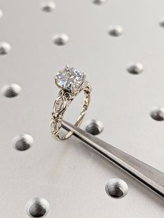 a close up of a diamond ring with a pair of scissors