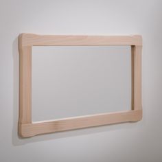 a wooden frame hanging on the wall with a mirror in it's center,