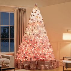 a white christmas tree with pink lights in a living room next to a couch and window