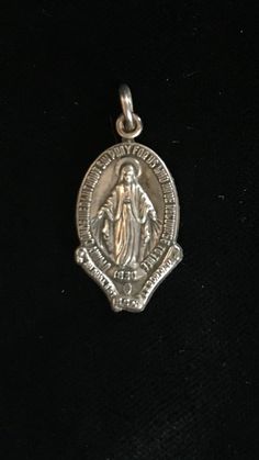 Vintage Kinney sterling Mary religious metal. This metal is marked Kinney also marked 1830 and measures 7/8”. In very good preowned condition. Engraved White Gold Jewelry For Commemoration, Antique Silver Jewelry With Miraculous Medal, Silver Miraculous Medal Memorial Jewelry, Vintage Sterling Silver Miraculous Medal Jewelry, Vintage Sterling Silver Miraculous Medal, Antique Jewelry With Miraculous Medal For Collectors, Vintage Silver Jewelry With Miraculous Medal, Mystic Ct, Blue Sapphire Bracelet