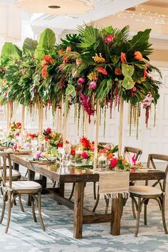 a long table with lots of flowers and greenery hanging from it's ceiling