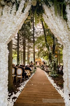 an outdoor wedding ceremony with white flowers and greenery on the aisle leading into the forest