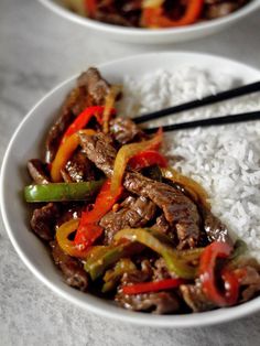 two white bowls filled with rice and beef stir fry