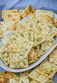 crackers with cheese and herbs on a white plate next to a blue cloth covered tablecloth