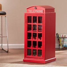 a red phone booth sitting on top of a hard wood floor next to a chair