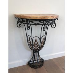 an iron and wood console table against a white wall in a room with hardwood flooring