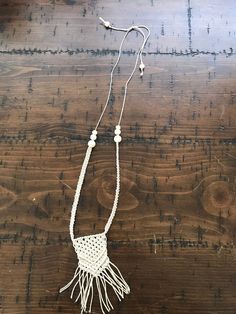 a white necklace with tassels and beads on a wooden surface, hanging from a string