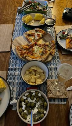 a table topped with plates and bowls filled with food next to corn on the cob