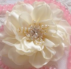 a close up of a flower on a lace doily with pink and white beads