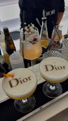 two glasses filled with drinks sitting on top of a counter