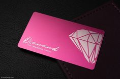 a pink diamond card sitting on top of a black surface