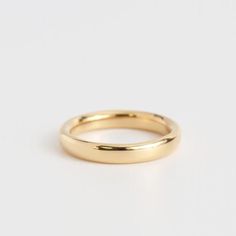 a yellow gold wedding ring on a white background