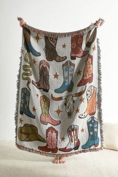 a blanket with cowboy boots on it hanging from the wall next to a white couch