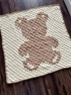 a crocheted teddy bear rug sitting on top of a wooden floor