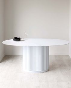 a white round dining table with two black plates on it