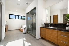 a large bathroom with a walk in shower next to a double sink vanity and wooden cabinets