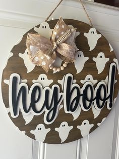 a wooden sign that says hey boo with ghost faces on it and a bow hanging from the front door