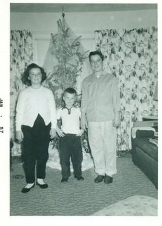 an old black and white photo of three people standing in front of a christmas tree