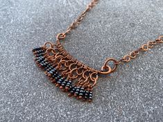 This fall-inspired handmade choker necklace features a bar pendant with shiny dark grey beaded fringe wire wrapped in high-quality pure copper. Flaunt this versitile statement necklace with a boho chic feel to compliment your style and elevate any outfit. A perfect fall accessory for the Halloween spooky season! 📐 SIZING:  Total length around is 17 inches. Pendant height is 1 inches, width is 2 inches. ✨ MATERIALS: Every item is 100% handmade and one-of-a-kind. The wire-wrapped copper jewelry is oxidized and polished to beautifully highlight details of the wirework. Since gemstones are unique, a slight variation from the colors pictured should be expected. 🙏🏼 CARE: This piece is made from natural copper wire and will darken over time. To renew the bright shine, use a polishing cloth or Copper Choker, Handmade Choker Necklace, Rustic Necklace, Bar Pendant Necklace, Copper Art, Grey Beads, Fringe Necklace, Fall Accessories, Bar Pendant