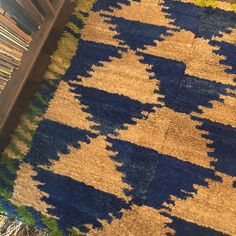 a blue and yellow rug on the floor next to a shelf with books in it