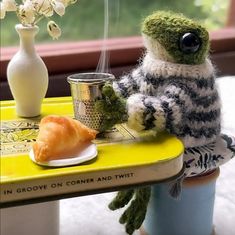 a stuffed animal sitting on top of a yellow table next to a cup and saucer