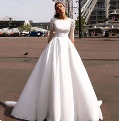 a woman in a white wedding dress standing on the street