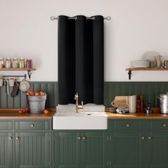 a kitchen with green cabinets and black curtains