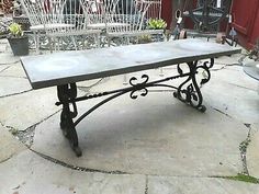 an old metal table sitting on top of a stone patio