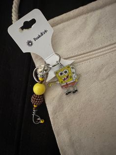 a spongebob keychain hanging from the side of a white piece of fabric