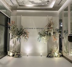 two tall vases filled with flowers sitting on top of a white floor next to windows