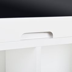 a white desk with a black top and bottom drawer on the left side, in front of a white wall