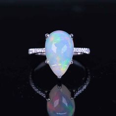 an opal and diamond ring on a black surface