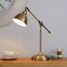 a desk lamp sitting on top of a wooden table next to a cup and saucer