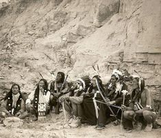 an old black and white photo of native american indians in front of a rocky cliff