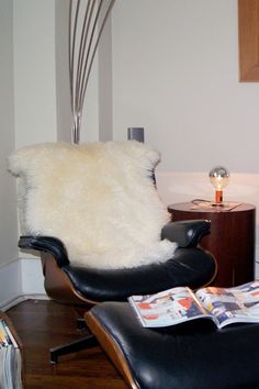 a chair and ottoman in a room with wood floors, white walls and wooden flooring