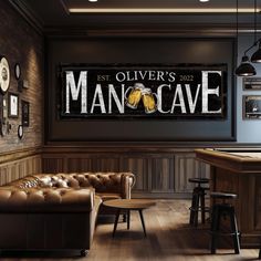 a man cave sign hanging in the corner of a room with leather couches and bar stools