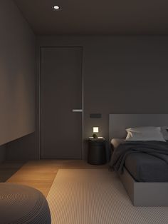 an empty bedroom with a bed, night stand and lamp on the side of the room