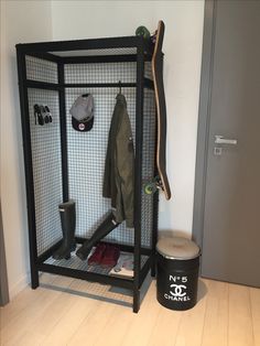 a room with a skateboard, coat rack and trash can on the floor next to it