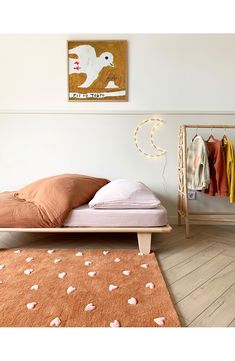 a bed sitting on top of a wooden floor next to a wall mounted art piece