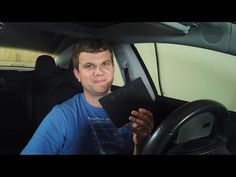 a man sitting in the driver's seat of a car holding up a book