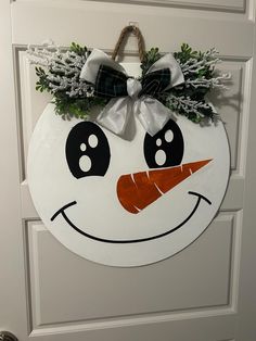 a white door with a snowman face painted on it and a bow hanging from the handle