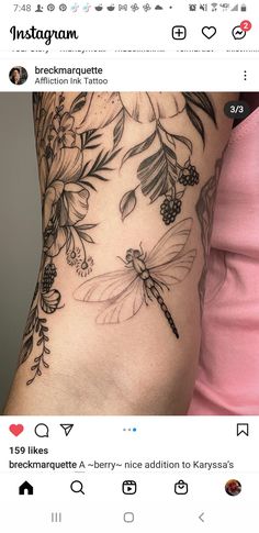 a woman's arm with flowers and dragonflys on the back of it