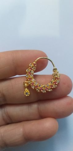 a person is holding a small yellow and pink beaded hooplet earring in their hand