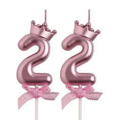 two pink birthday candles with the number twenty one on top and a bow tie around it