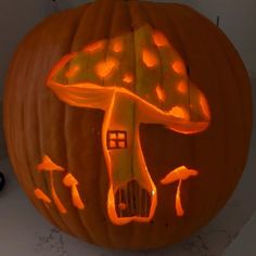 a carved pumpkin with an image of a mushroom on it's face and mushrooms coming out of the top