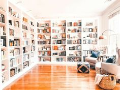 a living room filled with lots of bookshelves next to a couch and chair