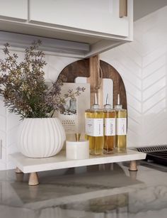 a white vase filled with flowers sitting on top of a counter next to bottles and candles