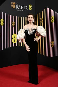 a woman in black and white gown standing on red carpet with her hands on her hips