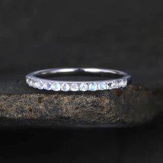 a white gold wedding band with round cut diamonds on the inside and outside, sitting on top of a rock