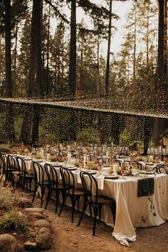 an outdoor dining area with tables and chairs set up for a party in the woods